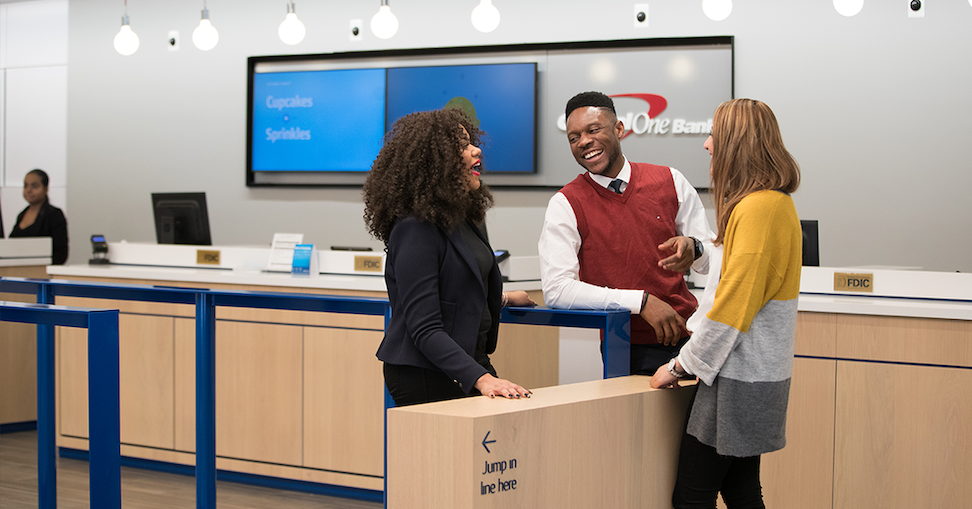 Two Capital One associates talk with a customer in a Capital One Bank